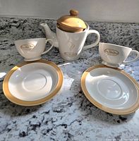 Front view of teapot, two cups and two saucers on granite counter, showing Tim Hortons logo and color scheme