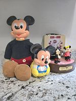 Overview of Mickey Mouse plush doll, plastic figurine, music box and metal tin