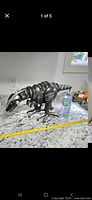 Front side view of the black Woowee Robo-Raptor toy on a kitchen counter with measuring tape and water bottle for scale