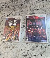 Two Wii game cases with front covers visible: Guitar Hero Aerosmith and The House of the Dead 2 & 3 Return.