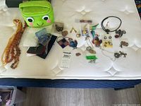 Entire lot on mattress with necklaces, pins, figurines, pouch visible