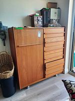 Front view of wood dresser showing drawers, door and casters