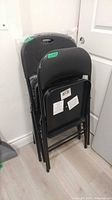 Stack of four black folding chairs showing two different designs