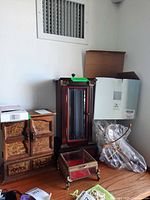 Two wood jewelry cabinets, brass-tone glass jewelry box, partial view of jewelry tree packaging