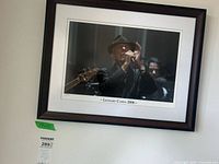 Full view of framed Leonard Cohen print on wall with size reference tag visible