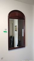 Full view of the mirror on wall showing arched top and wood frame