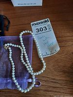 Necklace coiled beside lot card; clasp and pearls visible