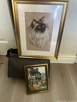 Both framed prints: cat portrait and cottage scene