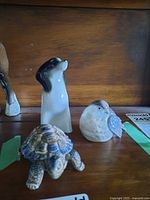 Front view of all three figurines showing turtle, dog, bird.