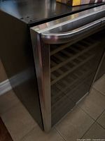 Exterior front view showing stainless steel-framed glass door, curved handle and black cabinet.