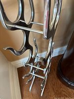 Close-up angled view of polished stainless steel wine rack showing curved bottle holders and metal rods for bottle support.