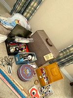 Overview of sewing supplies including tins, boxes, scissors, yard sticks, pin cushions, and fabric