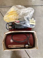 Photo of two compressors. Mobile Air Midwest Products compressor in box with hose. Craftsman compressor visible with yellow hose and control panel.