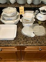 Wide view of lot on counter showing baking dishes with blue cornflower and vegetable patterns, storage containers and tea kettle.