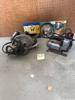 View of two Craftsman saws: a circular saw and a scroll saw, with extra blades and accessories in packaging behind them.