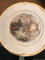 Dessert plate with a fox and deer in a forest scene, white porcelain with gold trimmed scalloped edges
