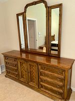 Full view of the large Drexel wood dresser with tri-panel mirror in a room.