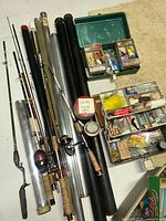 Fishing rods laid out with storage tubes, two-tier green tackle box and three-tier white tackle box trays visible