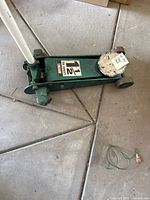 Side view of green Sears Roebuck floor jack showing the main body and wheels, label visible.
