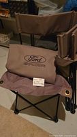 Small brown folding chair with Ford Explorer logo visible on backrest and seat fabric, photo also shows the chair frame and fabric details.