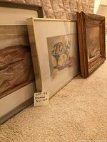 Photo showing full view of the three framed Southwest art pieces leaning against a wall on carpet.