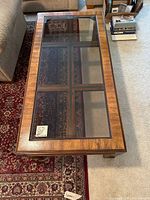 Top view of the rectangular wood framed glass top coffee table showing clear glass and wood grain.