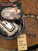 Photo showing silver-plated scalloped tray in box and other silver-plated trays and wire bowl, along with the 12 long-handled teaspoons with decorative ends.