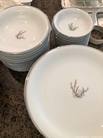 Stacked Noritake Sanford pattern dinner plates, small bowls, and saucers showing the white china with delicate taupe/gray botanical motif in center.