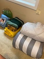 Stack of bedding items including comforter, blankets and heated blankets, showing size, color and condition.