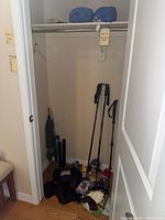 Overview photo of entryway closet with skis poles, umbrellas, gloves, rainwear, and other gear piled on the floor.