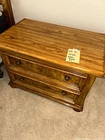 Front and side views of brown wood Drexel nightstand with two drawers and round metal knobs on carpeted floor.