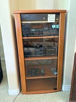 Stereo cabinet housing Onkyo amplifier, Kenwood CD players and remotes.