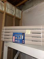 Photo showing stacked pack of 5 beige Sterilite 5-shelf plastic shelving units, with packaging label attached.