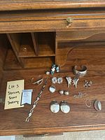 Wooden desktop with all jewelry laid out including bracelets, earrings, necklace, pendant frame and locket