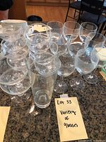Group of glasses on kitchen bar top including star pattern goblets, plain goblets, and a tall glass