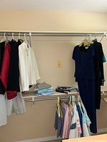 Photo of various women's long sleeve tops and folded clothes in a closet