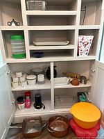 Cabinet overview showing Copper Chef pans, mixing bowls, mugs, bowls, baking dishes, utensils