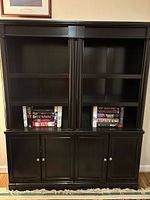 Front view of both matching black bookcases showing shelves and lower cabinets