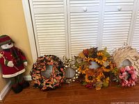 All wreaths lined against closet with snowman figure at left