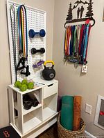 Overall view of stand showing resistance bands, dumbbells, kettlebell, yoga mats