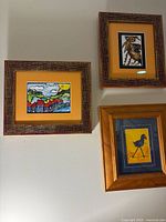 Three framed prints mounted on wall showing landscape and two bird artworks