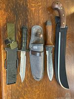 Group shot of three knives and accompanying sheaths
