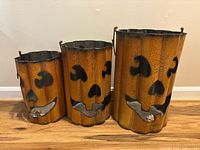 Front view of three graduated metal pumpkin buckets