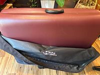 Maroon padded folding massage table inside black LifeGear carry bag