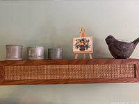 Top shelf with three ceramic tealight holders, miniature painting on easel, smoked grey glass bird figurine