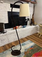 Full view of floor lamp showing curved wood frame, base, and shade