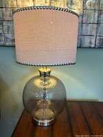 Full view of lamp lit showing hammered glass base and nailhead drum shade