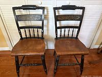Front view of both spindle back chairs showing seats, spindle backs, painted floral panels, wear