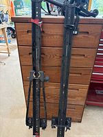 pair of rooftop bike rack rails leaning against cabinet with trunk rack partially visible