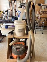 Overall view: Ridgid vacuum on lower shelf, bucket with cyclone separator above, hoses attached